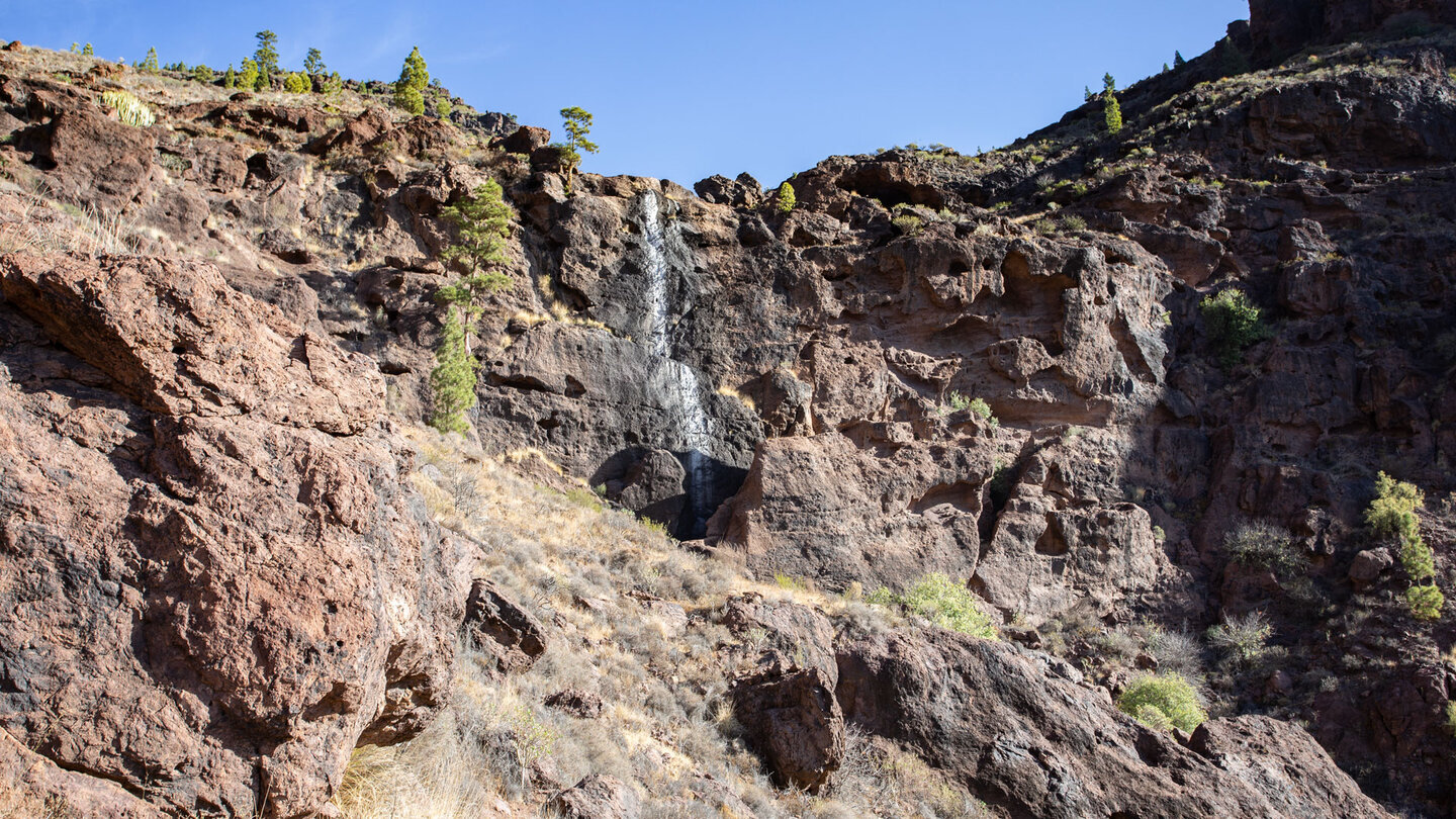 Am Wanderweg liegt ein trockener Wasserfall an einer steilen Felswand